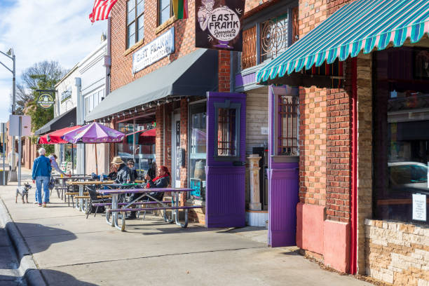 Monroe, NC, USA-28 Jan 2023: Sidewalk scene with people sitting at tables in front of East Frank's Superette & Kitchen.