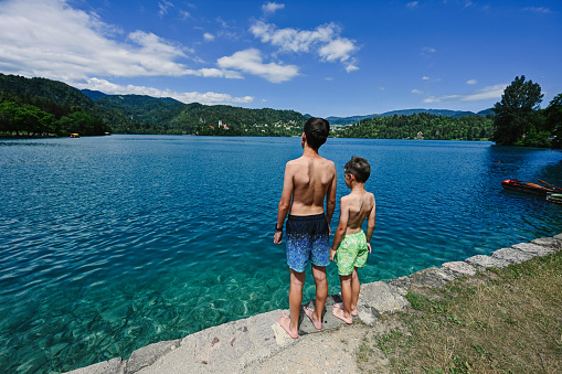 Back of two brothers stand in pier of view beautiful Bled Lake, Slovenia.