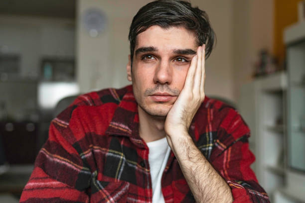 Sad unhappy handsome man sitting on the sofa and holding his forehead while having headache Sad unhappy handsome man sitting on the sofa and holding his forehead while having headache man regret stock pictures, royalty-free photos & images