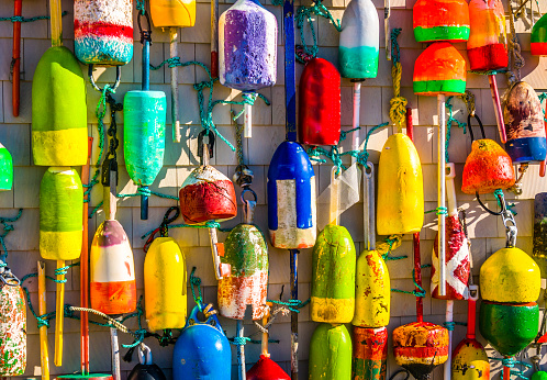 A large collection of lobster buoys that have washed ashore on nearby beaches decorate and adorn the outside wall of a  shop in Rock Harbor in Orleans, Massachusetts on Cape Cod.