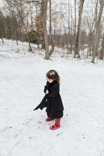 A 3-Year-Old Cuban-American Toddler Girl Experiencing the Cold Snowy Weather While Wearing a Coat, Boots & a Hair Bow on a Cold Snow Day in the Fresh White Fluffy Snow in Jackson, Ohio for Christmas in December 2022