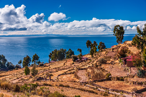 Lake Titicaca, view from Taquile Island, on background Peruvian shore. The lake is located at the northern end of the endorheic  Altiplano  basin high in the Andes on the border of Peru and Bolivia. The western part of the lake lies within the  Puno Region of Peru, and the eastern side is located in the Bolivian La Paz Department.The lake is composed of two  nearly separate sub-basins that are connected by the Strait of Tiquina which is 800 m (2,620 ft) across at the  narrowest point. The larger sub-basin, Lago Grande (also called Lago Chucuito) has a mean depth of 135 m (443 ft)  and a maximum depth of 284 m (932 ft). The smaller sub-basin, Winaymarka (also called Lago Pequeno, 