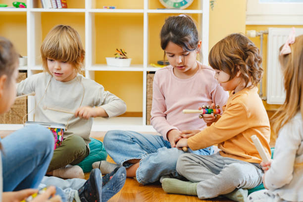 istock Kindergarten teacher with children sitting on the floor having music class, using various instruments and percussion. 1461189097
