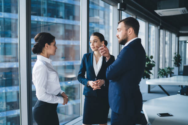 istock Positive colleagues having conversation while standing in office lobby 1461198558