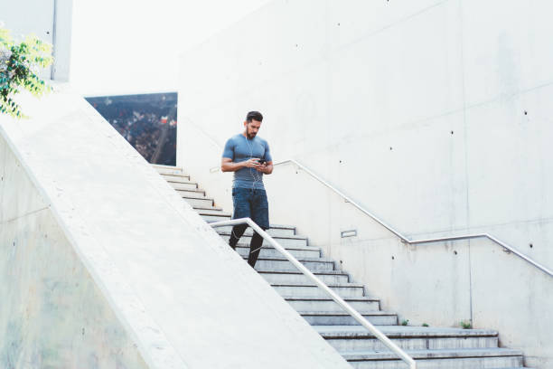 forte jogger navegando telefone descendo em escadas - men latin american and hispanic ethnicity southern european descent mature adult - fotografias e filmes do acervo