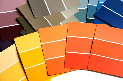 Color sample swatches on a table or desk. Swatches are in various shades of yellows, oranges, purple, blues and greens. Spring or fall color schemes. Interior design color pallet. Creative inspiration