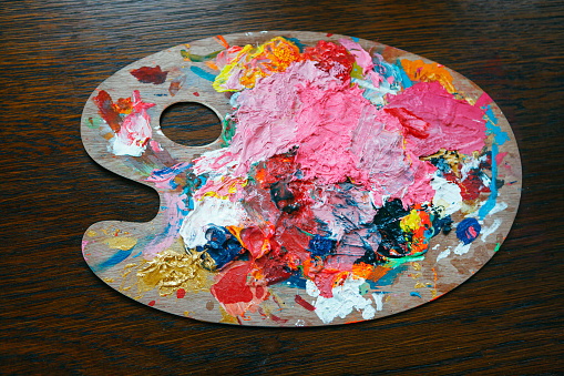 Palette of artist with colorful paints . Dirty colors palette