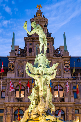 The historic Grote Markt and Brabo's Monument lit up in early evening. Brabo's statue was installed in 1887 and the Stadhuis (Town Hall building) was built in 1565.