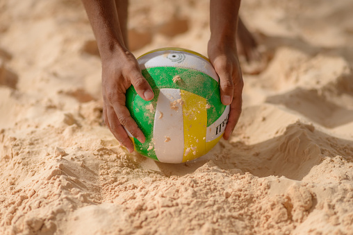 Detail of player catching ball on sand volleyball court. Volleyball – Latin America