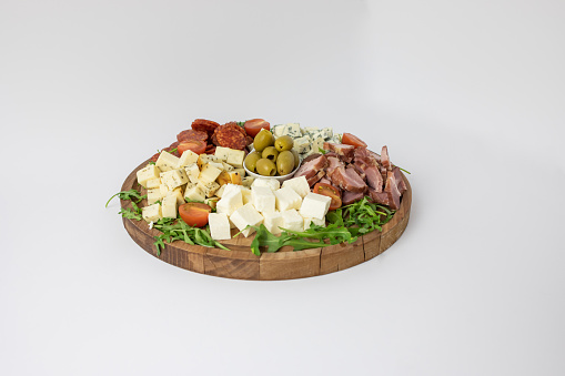 Close up of wooden plate with cheeses and cured meats