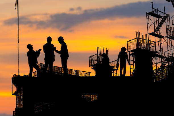 istock Silhouette of Engineer and worker checking project at building site background, construction site at sunset in evening time 1461211463