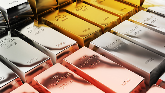 Gold and silver bars of various weights on a dark background. Selective focus.