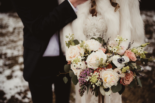 Bride and groom with wedding bouquet outdoors in winter
