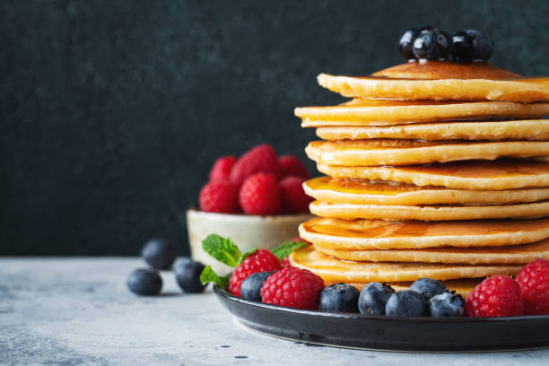 istock Delicious pancakes, with fresh blueberries, raspberry and maple syrup or honey on a dark background 1461214502