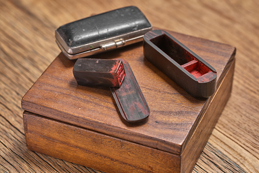 A Chinese ancient seal and two storage boxes are placed on a delicate wooden box, which rests on a rough, old wooden table. The signature seal was the main way for ancient people to leave their name when drawing or writing.