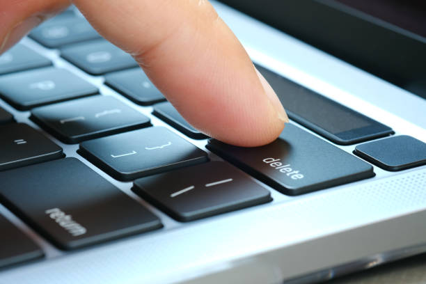 doigt de l'utilisateur de l'ordinateur, il appuie sur le bouton de suppression sur le clavier de l'ordinateur. - deleting photos et images de collection