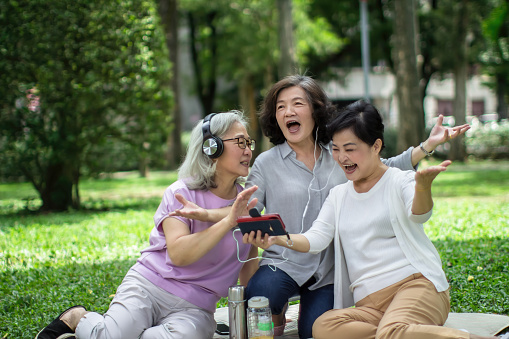 Three mature women having a great time while watching an entertaining video together on a smartphone. Friends enjoying technology and spending quality time.