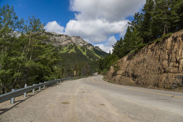 Tourism in the mountains - a road in the forest between the mountains. Great view, summer vacation, Banff, Alberta, Canada