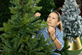 Woman is buying artificial Christmas tree in shop