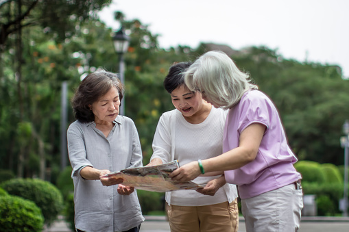 In this vibrant and adventurous stock image, three young women are seen huddled together, engrossed in studying a detailed map. Eager to embark on a thrilling journey, they plan their next escapade, filled with excitement and curiosity. The image captures the essence of wanderlust, teamwork, and a spirit of discovery, making it perfect for illustrating travel, exploration, and friendship-related concepts.