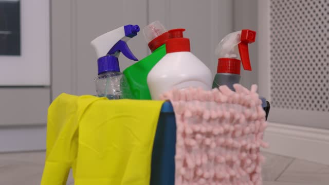 Brushes, bottles of cleaning products, sponges, rag and yellow rubber gloves