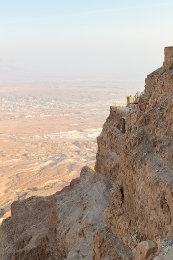 View during sunrise from the ruins of the fortress wall of the fortress of Masada to the ruins of the palace of King Herod and to the adjacent valley, in southern Israel