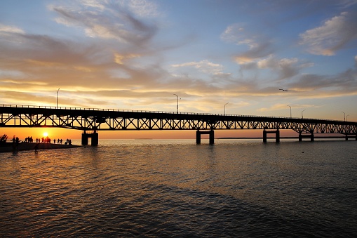Tourists enjoying beautiful sunset by Lake Michigan under Mackinac Bridge, Mackinaw City, Michigan, USA