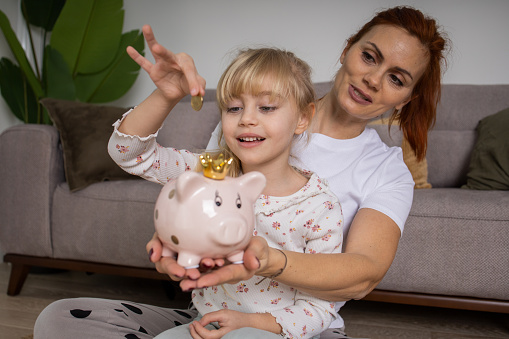 Happy family inserting money into piggy bank