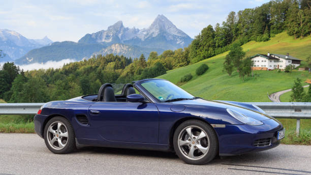 berchtesgaden, alemania - 25 de julio de 2021: roadster azul porsche boxster 986 con watzmann de montaña y panorama de niebla. el coche es un coche deportivo biplaza de motor central fabricado por porsche. - germany landscape nissan roadster fotografías e imágenes de stock