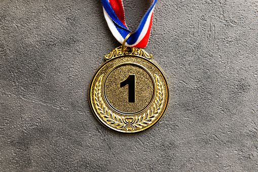 Simply flat lay design winner or champion gold trophy medal on concrete stone grey background. Victory first place of competition. Winning or success concept. Top view flat lay copy space