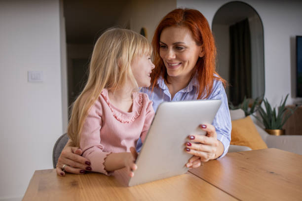 istock Cute little daughter and mother using digital tablet 1461246101
