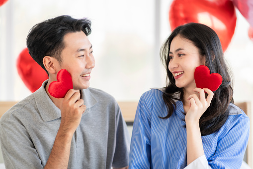 Asian couple Showing love surprise giving flowers or gifts to each other on important occasions such Valentine's Day birthdays or wedding anniversaries with love and warmth in bedroom of their home