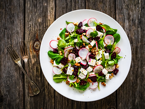 Beets salad with feta cheese on wooden background