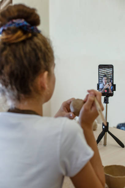 istock Teenage girl playing with modeling clay in pottery workshop, learning online using smartphone. DIY 1461261140