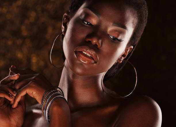 Beautiful young African woman with bright make up posing against a gold background.