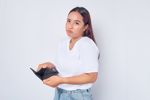 unhappy young blonde woman girl Asian wearing casual white t-shirt showing an empty wallet isolated on white background. people lifestyle concept