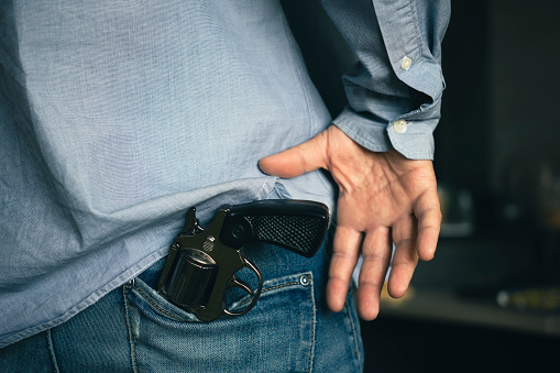 man takes a gun out of his pocket, the concept of self-defense or suppression, robbery. Legalization of firearms.