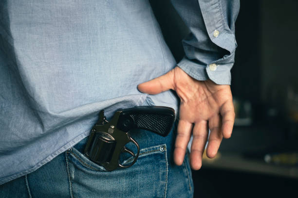 man takes a gun out of his pocket, the concept of self-defense or suppression, robbery. Legalization of firearms. a man takes a gun out of his pocket, the concept of self-defense or suppression, robbery. Legalization of firearms. wrongdoer stock pictures, royalty-free photos & images