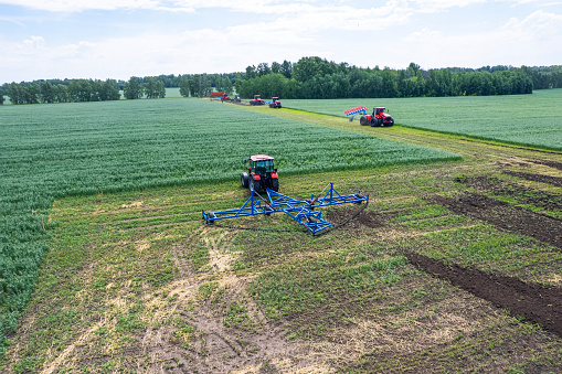 A large agricultural machine cultivates the land. The view from the top. Plowing land for planting crops. photos from the bird's eye view with a quadcopter