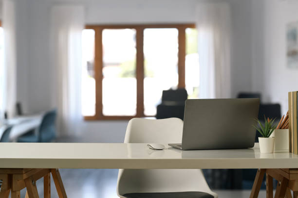 istock Comfortable home office interior with laptop computer, pencil holder, coffee cup and potted plant on white table. 1461270259