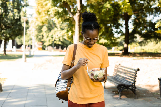 istock Happy Afro girl enjoying eating salad while walking 1461270556