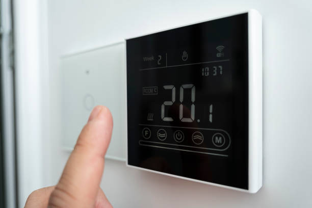 istock 20 degrees Celsius room comfortable temperature. electronic thermometer on the wall. Close-up of a Caucasian male hand adjusting modern wall-mounted digital thermostat. 1461270802