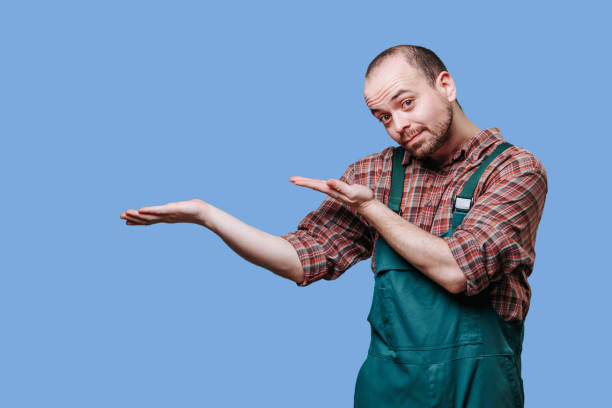 istock With a surprised look on his face, the man dressed in a coverall workman has his hands spread 1461273397