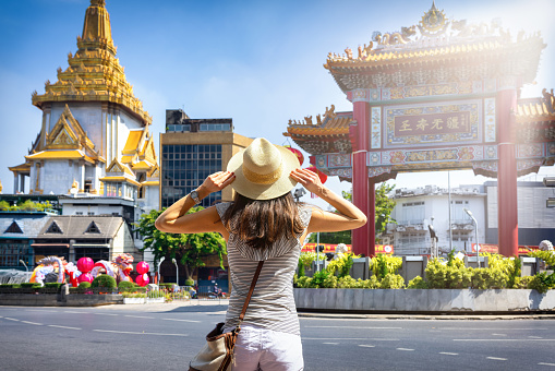 A tourist woman on sightseeing tour stands in front of the Chinatown Gate at Bangkok City, Thailand