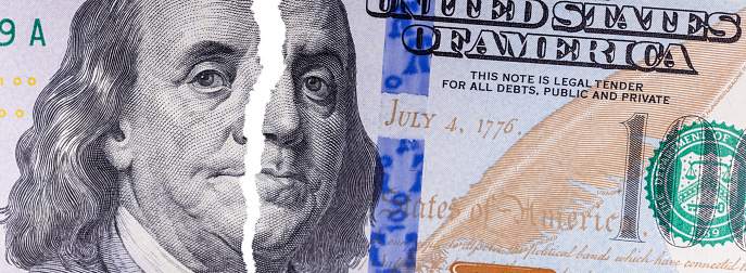 A closeup shot of torn hundred dollar note with a portrait of Benjamin Franklin
