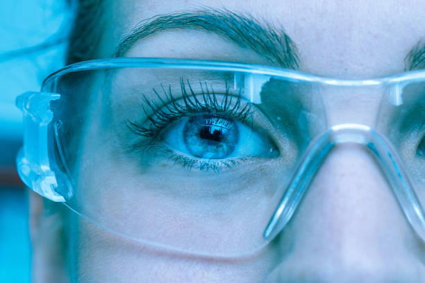 A close up view on the eyes of a pretty young Caucasian woman A close up view on the eyes of a pretty young Caucasian with lab glasses. Blue athmosphere protective eyewear stock pictures, royalty-free photos & images