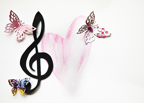 Three cut-out colorful paper butterflies and a musical treble clef