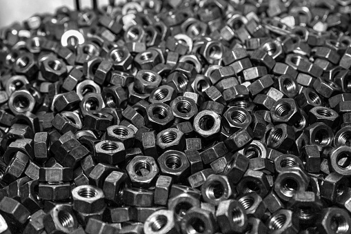 A selective focus shot of stainless steel bolts in a pile