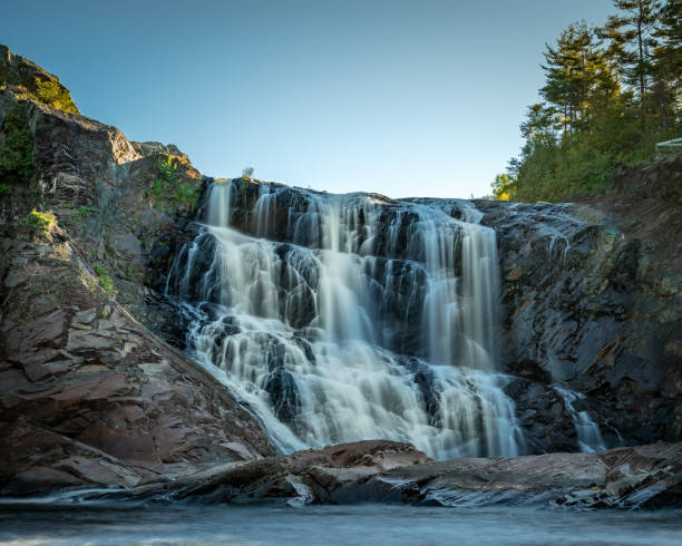 istock Mesmerizing waterfall over the rock formations in the forest against a clear blue sky 1461284205