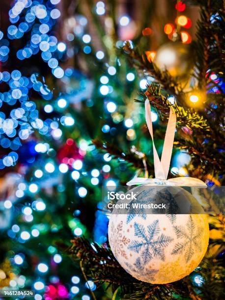 Closeup Of Christmas Tree Hanging Bauble With Colorful Lights Blurred Background Stock Photo - Download Image Now
